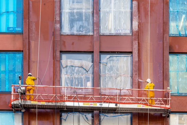 Two men working on a commercial building that needs to be refurbished from the outside, whilst still being used.