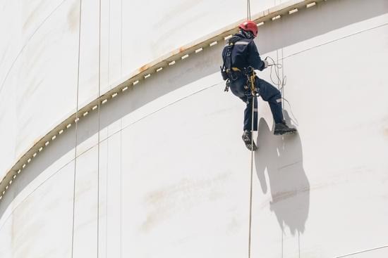 A male worker safely carrying out a building inspection using rope access.